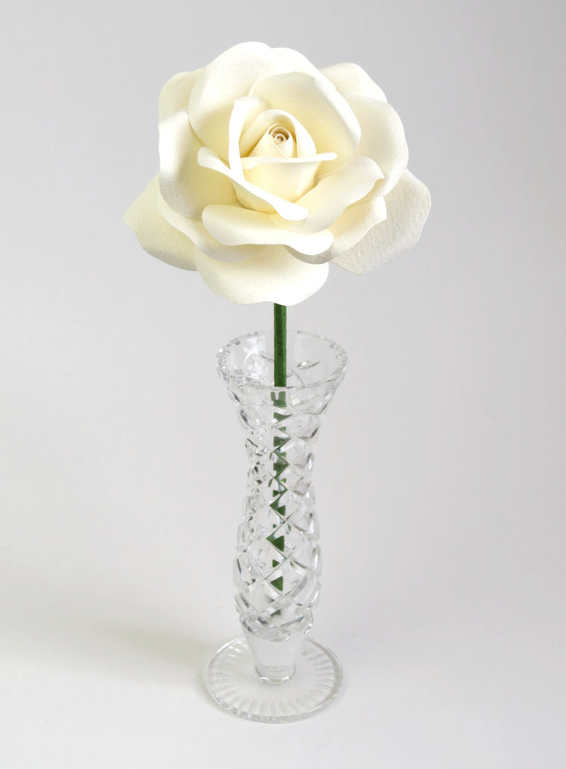 Leafless white cotton paper rose standing in a slender glass vase
