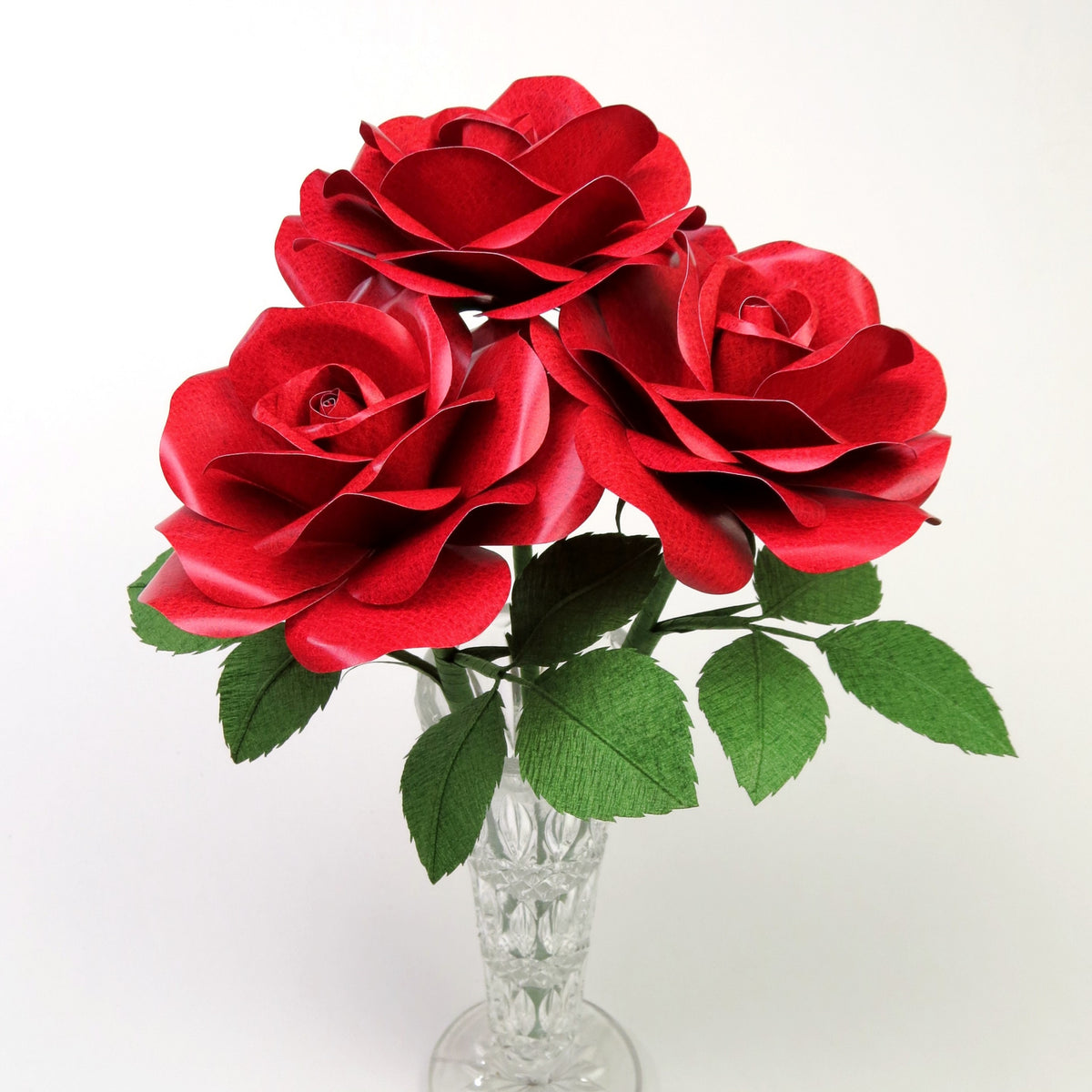 Bouquet of three red leather grain paper roses sitting in a crystal vases 