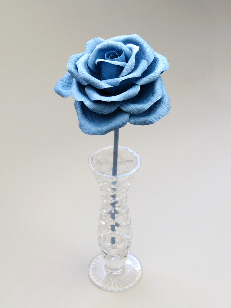 Leafless china blue crepe paper rose standing in a slender glass vase