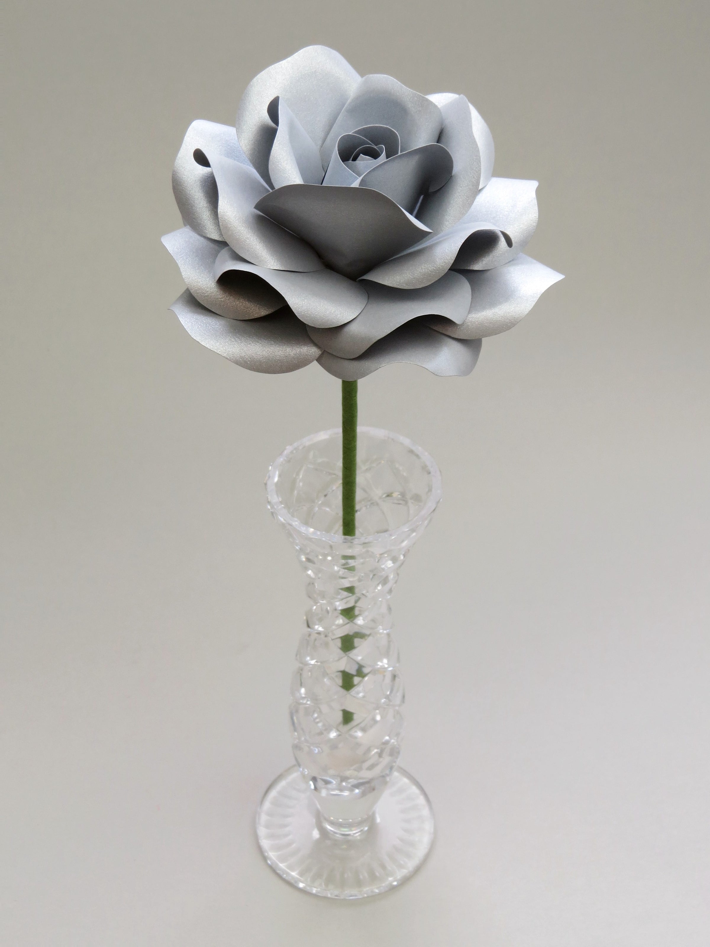 Leafless steel paper rose standing in a slender glass vase