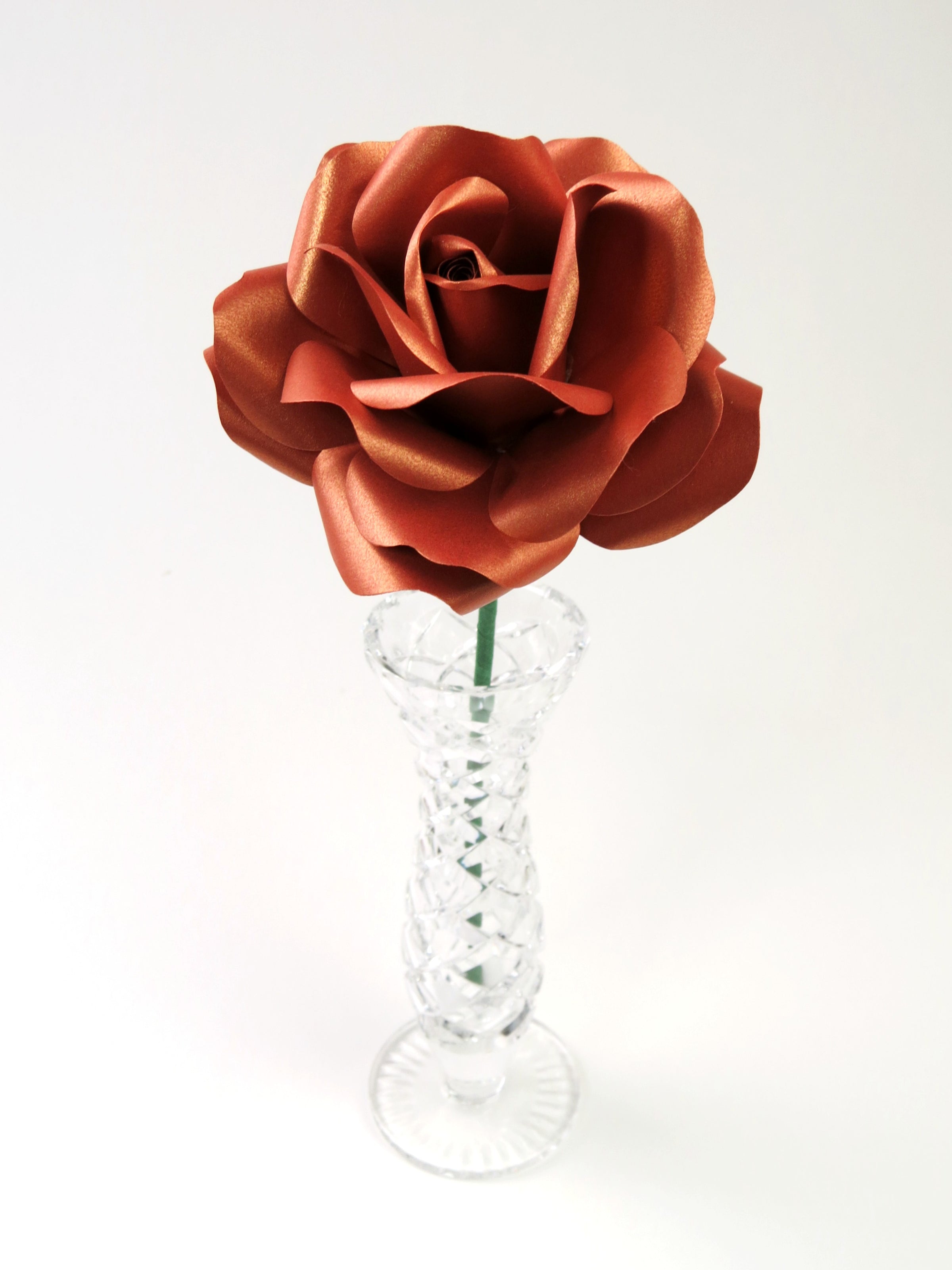 Leafless copper paper rose standing in a slender glass vase