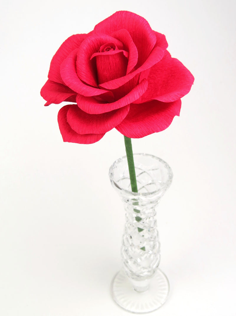 Leafless red paper rose standing in a slender glass vase
