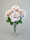 Bouquet of four white linen grain paper roses sitting tightly in a crystal vase with some ivy green leaves showing, set against a light grey background