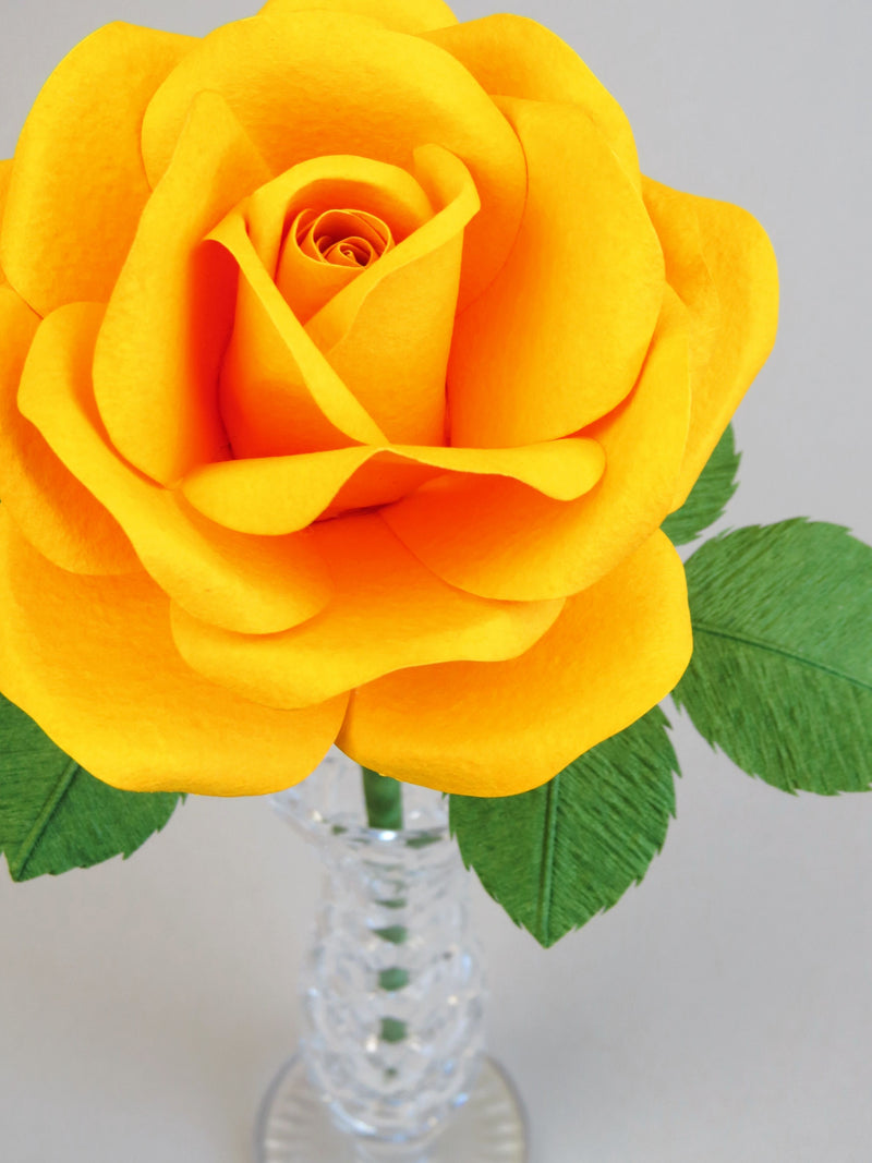 Close up detail of the texture on the petals of a bright yellow cotton paper rose in a slender glass vase