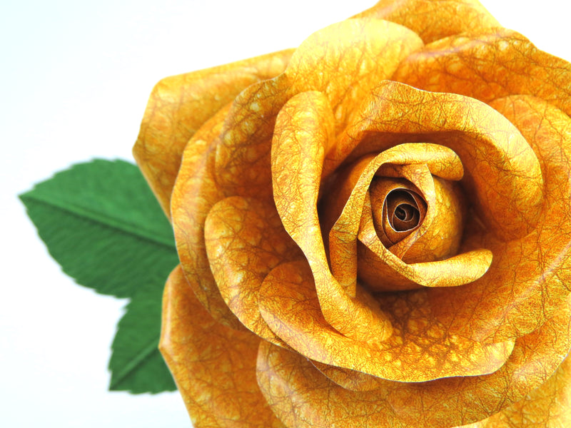 Close up detail of the texture on the petals of a bright yellow leather grain paper rose