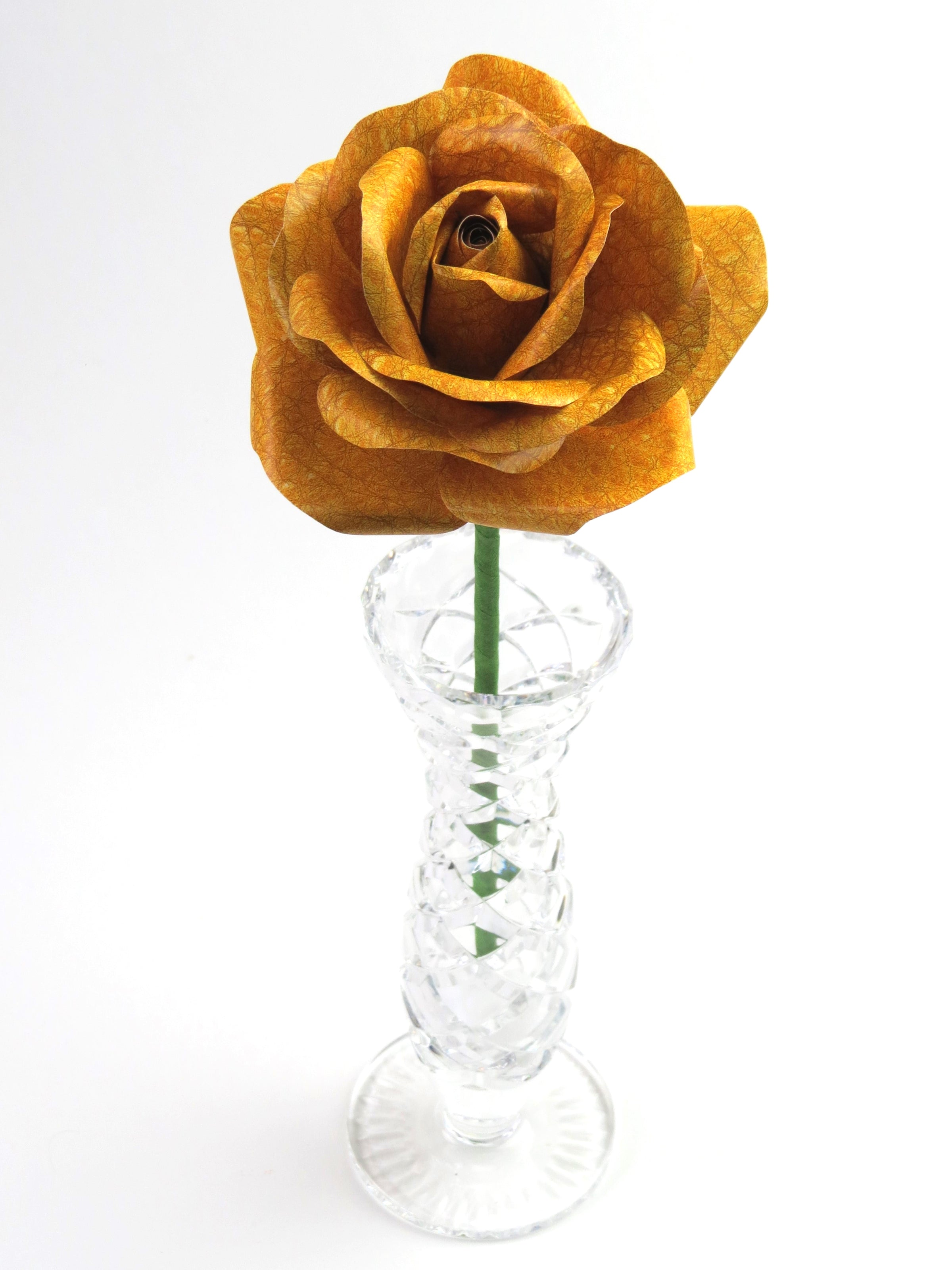 Leafless yellow leather grain paper rose standing in a slender glass vase