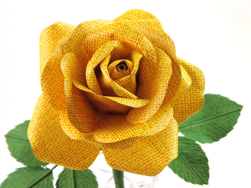 Close up detail of the texture on the petals of a bright yellow linen grain paper rose
